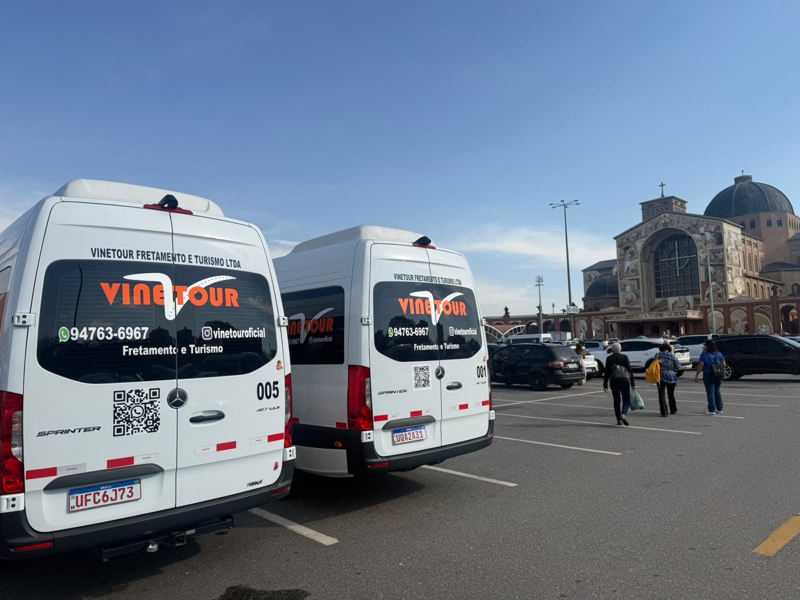 Duas vans Sprinter da Vinetour vistas pela traseira no Santuário de Aparecida